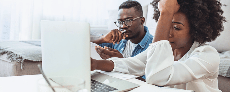 black man and black woman looking at laptop frustrated