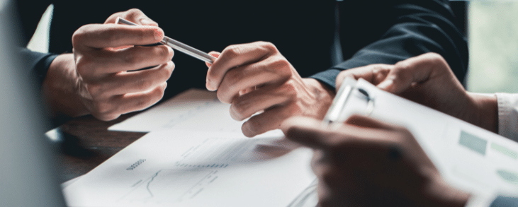 white hands holding pen with black hands holding clipboard