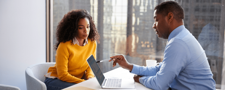 woman and man sitting at desk reviewing document on tablet